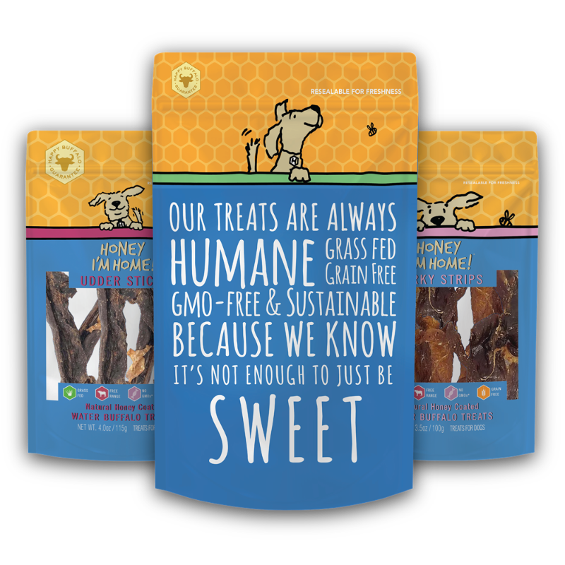 Three bags of Humane Grass Fed Grain Free dog treats arranged in a fan shape on a white background. The center bag is blue with white text reading 'OUR TREATS ARE ALWAYS HUMANE GRASS FED GRAIN FREE BECAUSE WE KNOW IT'S NOT ENOUGH TO JUST BE SWEET'.